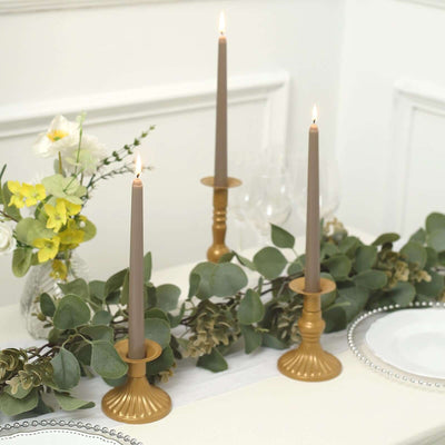 Elegant gold candlesticks with gray candles on a decorated table.