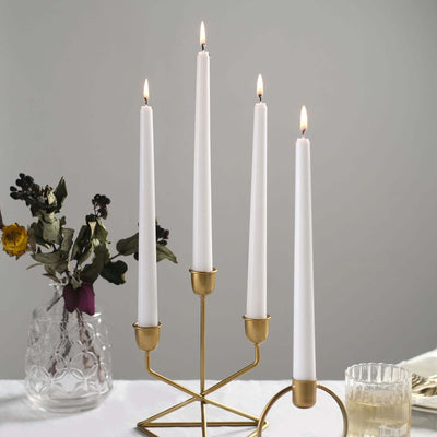 Elegant brass candle holder with four white candles lit, styled with flowers.