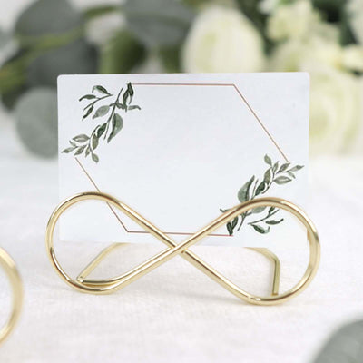 Gold infinity card holder with floral design card on a blurred background.