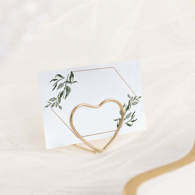 Gold heart-shaped card holder with a floral design backdrop.