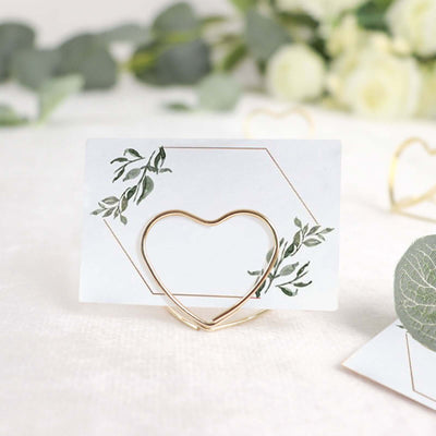 Heart-shaped gold card holder with floral design on a white background.