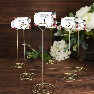 Gold table number holders with floral cards for weddings or events.