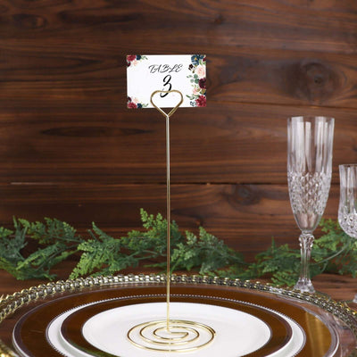 Gold table number holder with floral design for event decoration.