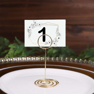 Gold table number holder with floral design card displaying the number one.