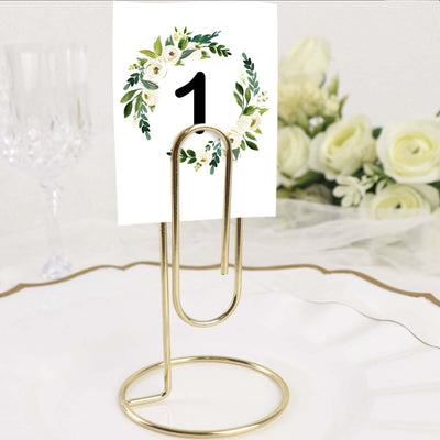 Gold metal table number holder with floral design card, perfect for events.