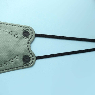 Gray leather face mask with black elastic straps on a blue background.