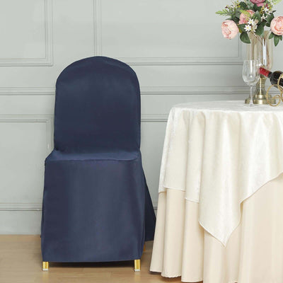 Elegant navy chair cover draped over a chair beside a table with floral arrangement.