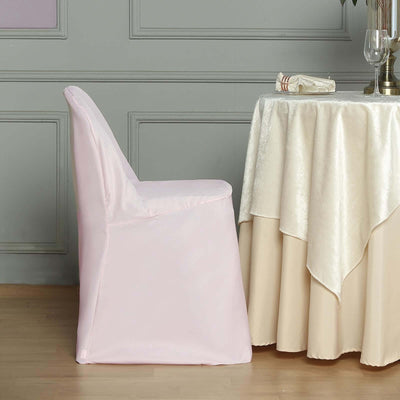 Pink chair cover draped over a chair beside a table with a tablecloth.
