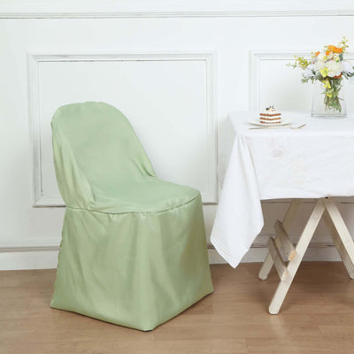 Green chair cover draped over a dining chair beside a table with flowers.