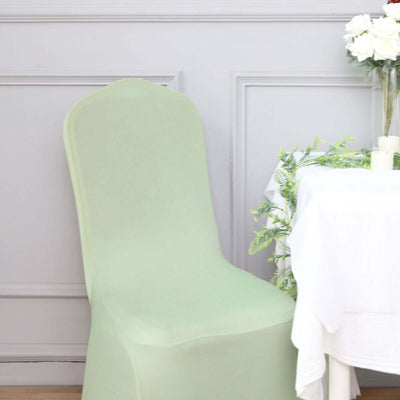 Green chair cover on a dining chair next to a table with decor.