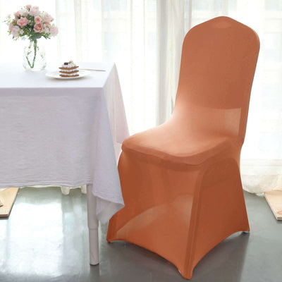 Orange chair cover draped over a chair next to a table with flowers and dessert.