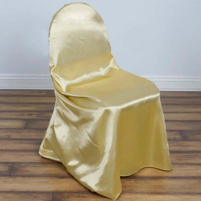 Gold satin chair cover draped over a chair on a wooden floor.