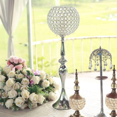 Decorative silver lamp with crystal accents on a table with flowers and candles.