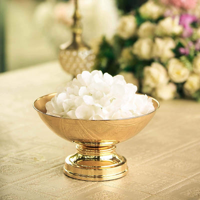 Gold bowl filled with white flowers on a table.