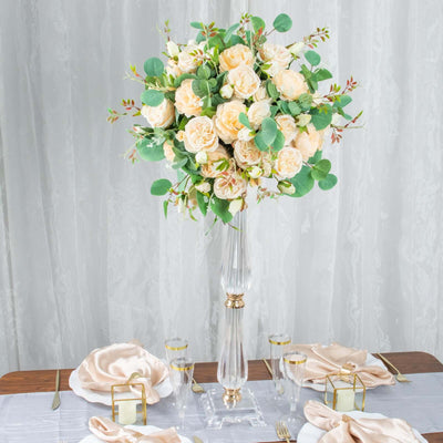 Elegant floral centerpiece with roses and greenery on a dining table setting.