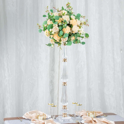 Elegant floral centerpiece with roses and greenery in a tall glass vase.