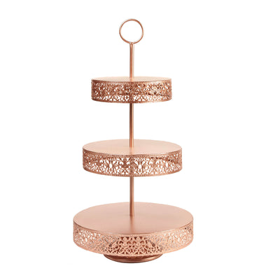 Three-tiered rose gold cake stand with decorative cutouts.