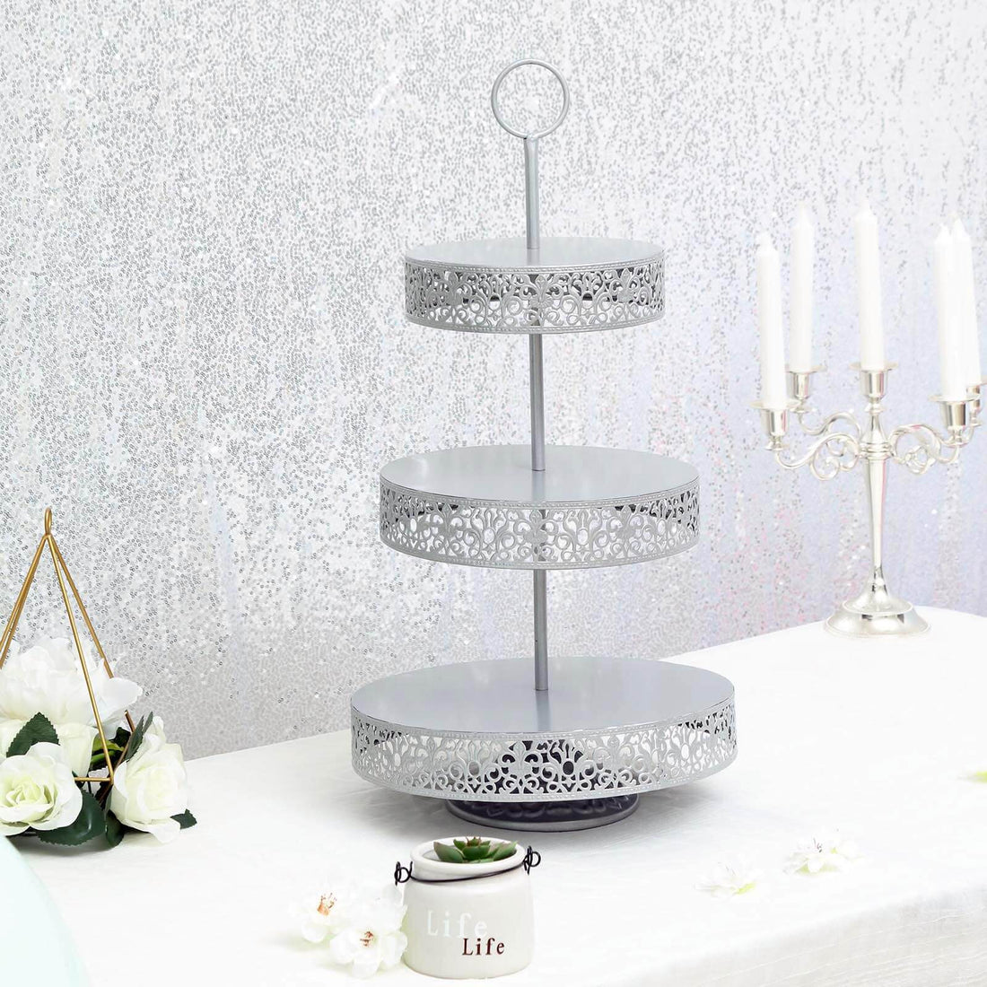 Three-tiered decorative metal serving stand with intricate cutouts.