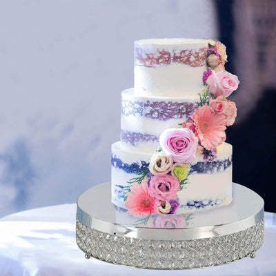 Decorative three-tier cake adorned with pink and purple flowers on a silver stand.