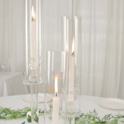 Elegant glass candle holders with lit candles on a table setting.