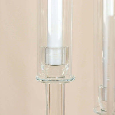 Elegant glass candle holder with a clear base and white candle inside.