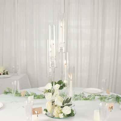 Elegant candle centerpiece with roses and greenery on a table setting.