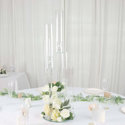 Elegant glass candle holders with white roses on a table setting.