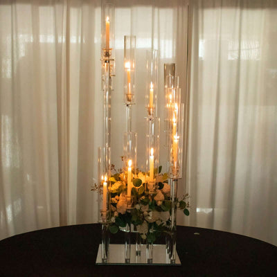 Elegant candle holder centerpiece with lit candles and floral arrangement.