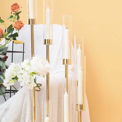 Elegant gold candle holders with clear glass tubes and white candles.