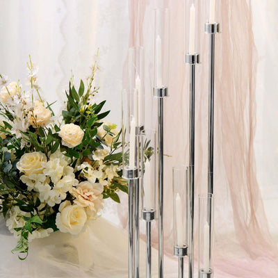 Stylish candle holder with multiple glass tubes and silver accents, surrounded by flowers.