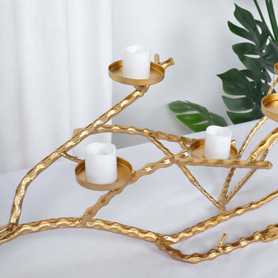 Gold branch candle holder with white candles and decorative greenery.