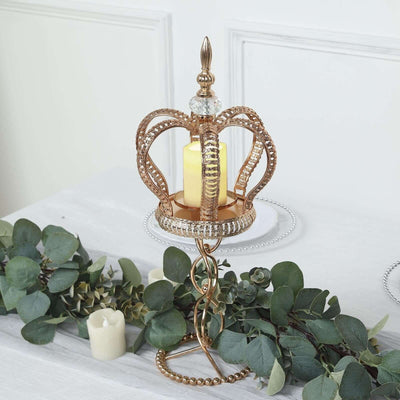 Gold crown candle holder with a lush green garland and candles.