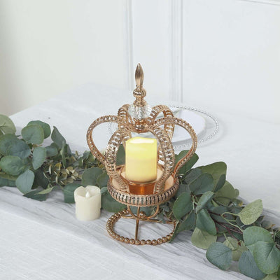 Gold crown candle holder with a lit candle and greenery decor.