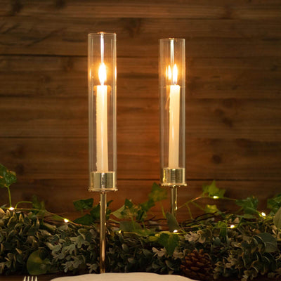 Elegant candle holders with tall glass tubes and white candles, glowing warmly.