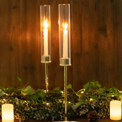 Elegant candle holders with candles, surrounded by greenery and soft lighting.