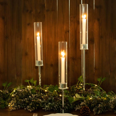 Elegant candle holders with candles, surrounded by greenery and warm lights.