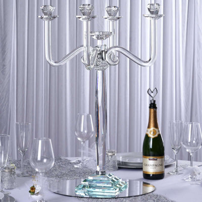Elegant glass candelabra centerpiece with champagne bottle on a dining table.