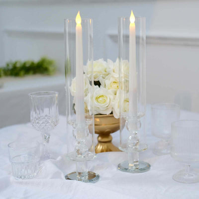 Elegant candle holders with candles and floral centerpiece on a table.