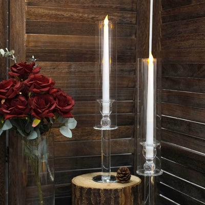 Elegant candle holders with white candles and decorative roses in a rustic setting.