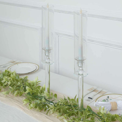 Elegant glass candle holders with white candles and greenery decor.