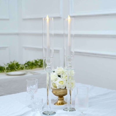 Elegant glass candle holders with candles and roses on a table setting.
