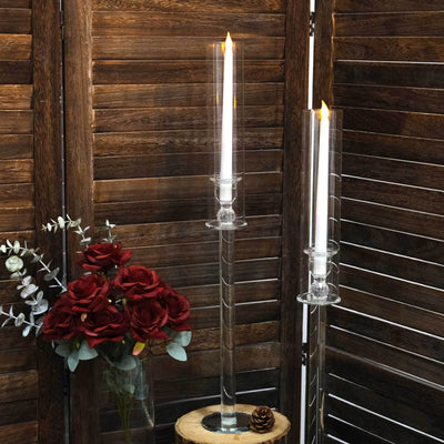 Elegant glass candle holders with lit candles and red roses in a decorative setting.