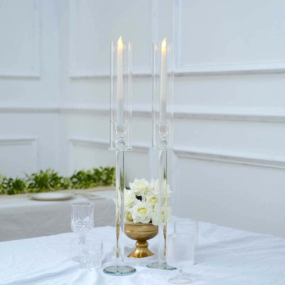 Elegant glass candle holders with candles and flowers on a table setting.