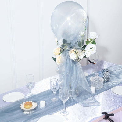 Decorative table setting with flowers, glassware, and a silver balloon centerpiece.