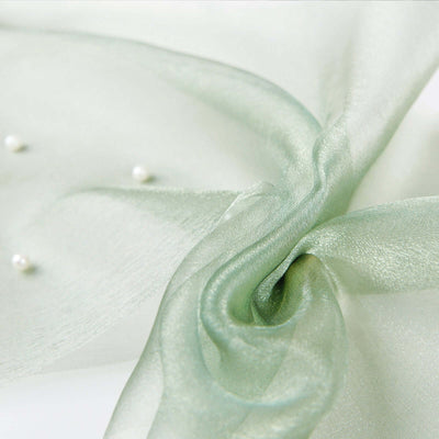 Sheer green fabric with pearl accents, elegantly twisted.