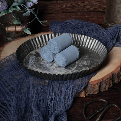 Blue rolled towels in a rustic metal tray on a wooden surface.