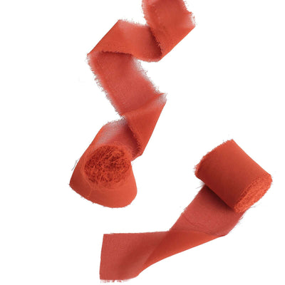 Orange fabric ribbon in a flowing cutout design on a white background.