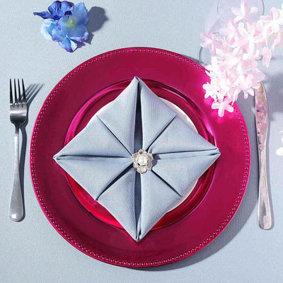 Elegant blue napkin folded on a vibrant pink plate, styled with floral decor.