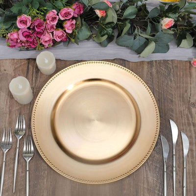 Gold charger plate on a rustic wooden table with floral decor and candles.