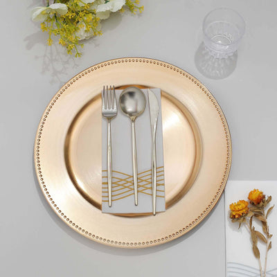 Elegant gold charger plate styled with silver cutlery and decorative napkins.